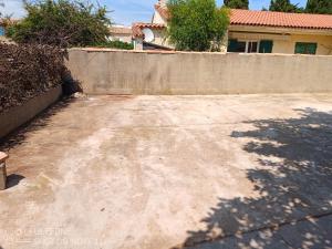 a concrete parking lot in front of a fence at La maison à la mer de Mamé Rosette in Port-de-Bouc