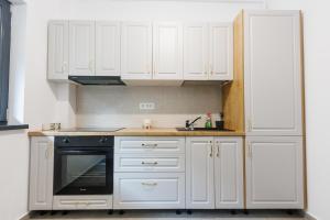 a kitchen with white cabinets and a black dishwasher at Confort Apartment in Iaşi