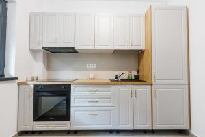 a kitchen with white cabinets and a black oven at Confort Apartment in Iaşi +9 photos