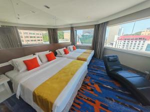 a hotel room with two beds and a chair at Hotel Capital Kota Kinabalu in Kota Kinabalu +37 photos