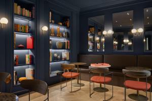 a restaurant with stools and tables in a room with books at Casa Laveni in Milan +39 photos