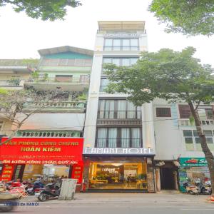 a tall white building with a store on a street at L'amant de Hanoi Hotel in Hanoi
