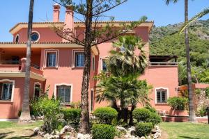 a pink house with palm trees in front of it at vituco34 in Mijas