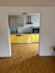 an empty kitchen with yellow cabinets and a wooden floor at Spacious Rooms Near Center in Ljubljana
