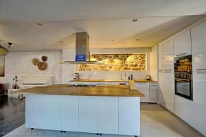 a kitchen with white cabinets and a wooden counter top at Meublés de tourisme Griotte et Cannelle in Bergbieten