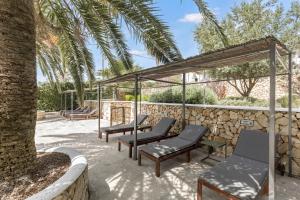 a patio with chairs and a stone wall at Villa Linda in Punta Prima