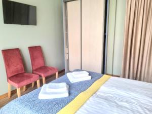 a bedroom with two chairs and a bed with two towels at GMM Namai in Palanga