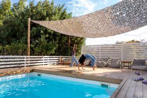 two people are doing yoga next to a swimming pool at Evaeri villa in Artemida +37 photos