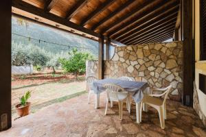 a table and chairs on a patio with a stone wall at Baglio Montoleone in Castelluzzo +49 photos
