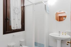 a white bathroom with a sink and a shower at Baglio Montoleone in Castelluzzo