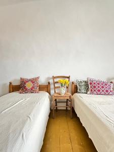 a room with two beds with a chair and a vase of flowers at Stúdió apartman in Kővágóörs