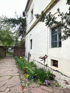 a garden in front of a white house with flowers at Stúdió apartman in Kővágóörs +5 photos