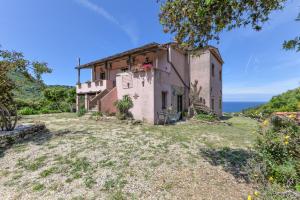 an old house on a hill with the ocean in the background at Agriturismo Amandolo in Cavo