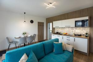 a living room with a blue couch and a kitchen at Pelso Lodge Alsóörs in Alsóörs