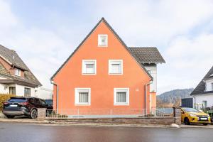 a orange house with two cars parked in front of it at Ferienwohnung Schuhmacher in Donaueschingen