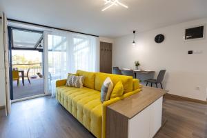 a living room with a yellow couch and a table at Pelso Lodge Alsóörs in Alsóörs
