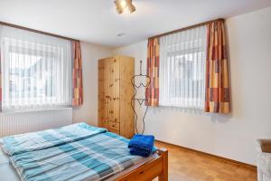 a bedroom with a bed and two windows at Ferienwohnung Schuhmacher in Donaueschingen