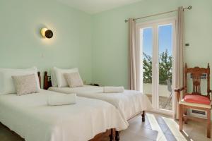 two beds in a white room with a window at Aegean Villas Ios in Ios Chora +58 photos