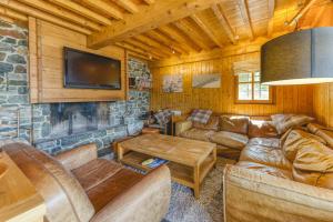 a living room with leather furniture and a stone wall at Gabbro-Chalet Moderne Tout Confort in Villard-Reculas