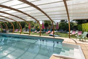 a swimming pool with a pergola and chairs at Domaine de Lestroué - Île de Groix in La Vraie-Croix