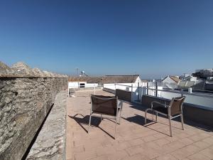 a patio with two chairs and a stone wall at Casa Privada in Vejer de la Frontera