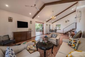a living room with couches and a flat screen tv at SaffronStays Sparrow's Nest in Mahabaleshwar