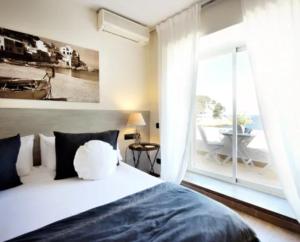 ein Schlafzimmer mit einem Bett und einem großen Fenster in der Unterkunft Hostal Sa Tuna in Begur