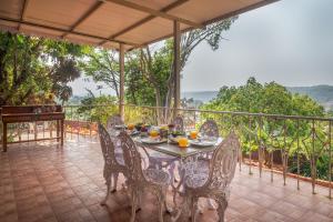 a table and chairs on a balcony with a view at SaffronStays Sparrow's Nest in Mahabaleshwar