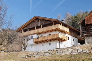a building with a wooden balcony on top of it at Herzleierhof Rodeneck in Rodengo