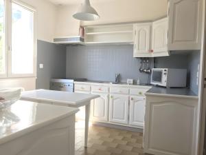 a kitchen with white cabinets and a microwave at Le Nid Marin - 76 in Pornic