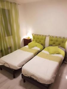 two beds in a room with green curtains at Le Nid Marin - 76 in Pornic