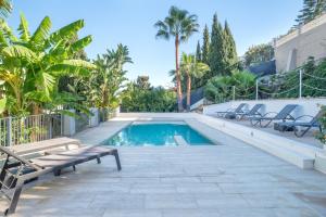 a swimming pool with a bench and palm trees at Villa Jazmin in Mijas Costa