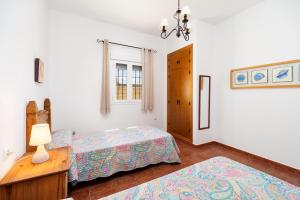 a bedroom with two beds and a table with a lamp at Luisa 3 in Conil de la Frontera +17 photos