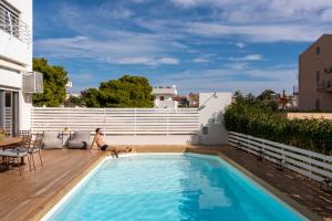 a woman sitting on a deck next to a swimming pool at Evaeri villa in Artemida