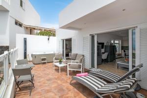 a patio with chairs and a couch on a balcony at Garden Apartment in Tías