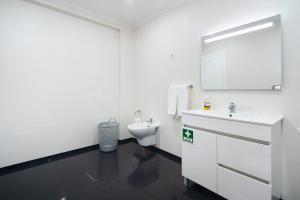 a white bathroom with a sink and a toilet at Windmill Açores Suite in Furnas +16 photos