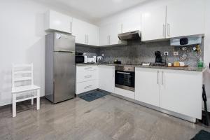 a kitchen with white cabinets and stainless steel appliances at Windmill Açores Suite in Furnas
