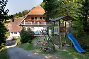 a playground with a slide and a house with a balcony at Schornhof in Oberwolfach