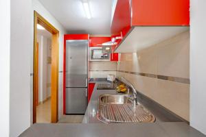 a kitchen with a stainless steel sink and red cabinets at Puerto Playa 2 in Puerto del Rosario