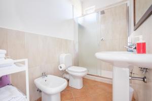 a white bathroom with a toilet and a sink at Medusa Apartment in Taormina