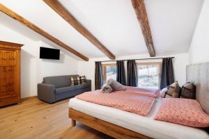 a bedroom with a bed and a couch at Herzleierhof Rodeneck in Rodengo