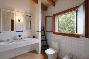 a bathroom with two sinks and a toilet and a window at Finca Port Vert in Son Servera +27 photos