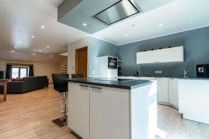 a kitchen with white cabinets and a living room at Hôtel La Métairie in Trois-Ponts