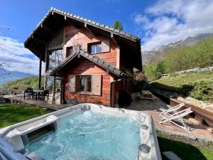 a hot tub in front of a house at Chalet Coeur de Savoie in Cléry