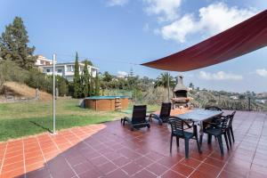 a patio with a table and chairs and a grill at La Finca de Teror in Teror