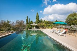a swimming pool with two chairs and an umbrella at La Farneta in Monteriggioni