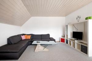 a living room with a black couch and a tv at Ferienwohnung Lange in Waldstetten
