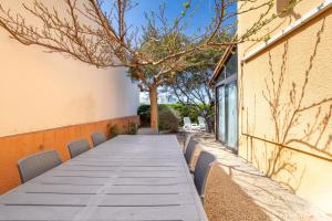 a long wooden table with chairs next to a building at Maison 4 chambres fb112 in Le Barcarès