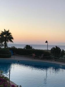 a swimming pool with a sunset in the background at Casa Orchidea in Calatabiano