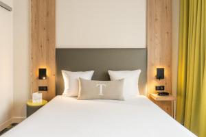a bedroom with a large bed with a white pillow with the letter t at Hôtel Maison Turenne in Colmar